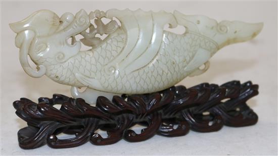 A Chinese pale celadon jade fish-dragon plaque, 18th century, 14cm, with a rosewood stand carved as waves